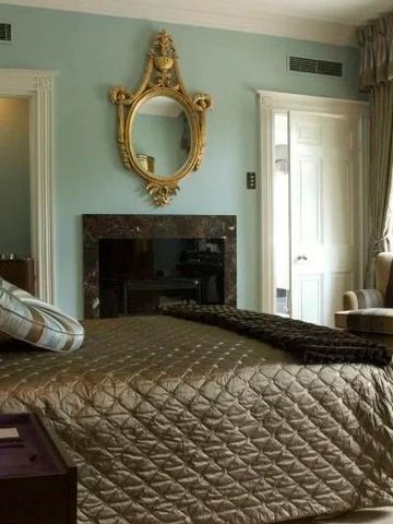Luxuriöses Schlafzimmer mit antikem Spiegel und eleganten Stoffen.