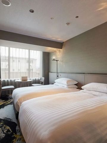 Modernes Hotelzimmer mit zwei Einzelbetten, stilvoller Einrichtung und großem Fenster