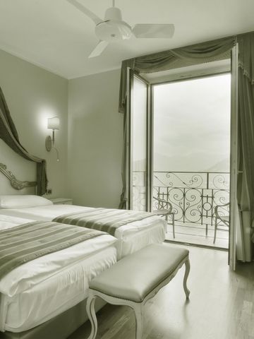 Helles Zimmer mit zwei Betten und Blick auf einen Balkon.