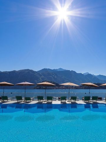 Infinity Pool mit Liegen und Sonnenschirmen vor der Kulisse des Comer Sees