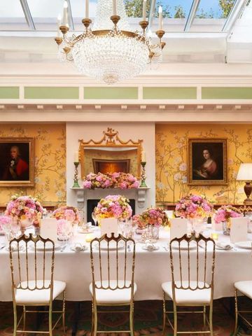 Prunkvoll gedeckter Tisch mit Blumenarrangements unter Kristallleuchter