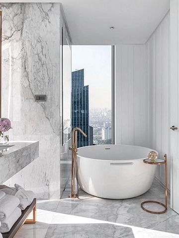 Luxuriöses Badezimmer mit freistehender Wanne und Blick auf die Stadt.