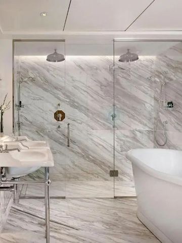 Luxuriöses Badezimmer mit Marmorwänden und freistehender Badewanne