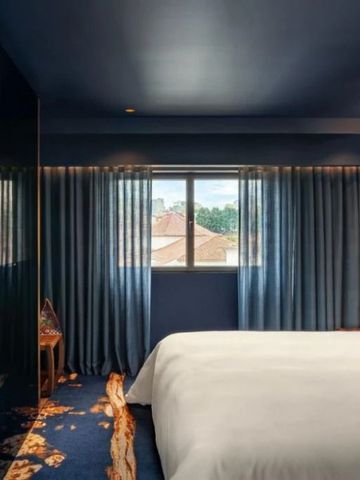Modernes Schlafzimmer mit blauen Vorhängen und stilvollem Lichtdesign.