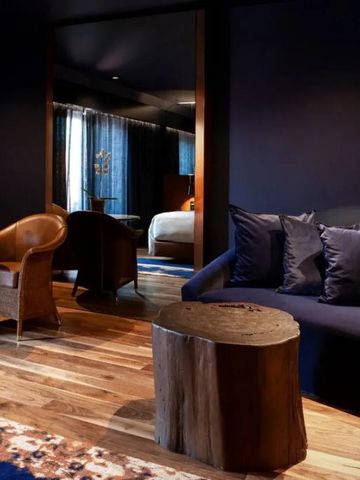 Gemütlicher Wohnbereich im Hotelzimmer mit Ledersesseln und Holztisch.