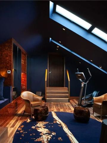 Luxuriöses Fitnesszimmer unter Dachschräge mit moderne Ausstattung und bequemen Sitzen.