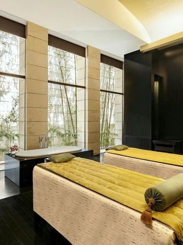 Luxuriöser Spa-Behandlungsraum mit zwei Massageliegen und großen Fenstern