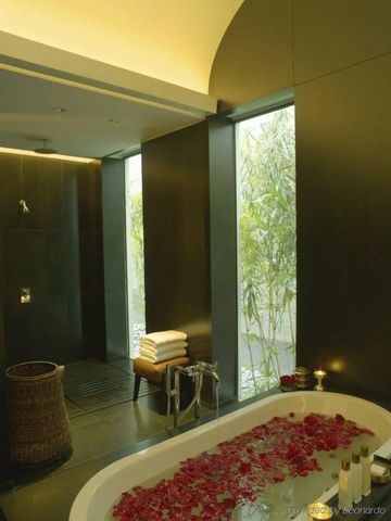 Luxuriöses Badezimmer mit großer Badewanne und Blick auf Bambus.