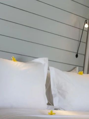 Elegantes Schlafzimmer mit weißer Bettwäsche und moderner Lampe
