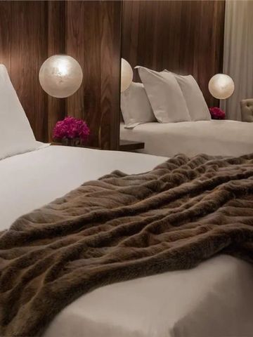 Stilvolles Doppelbett mit Samtdecke und eleganter Beleuchtung