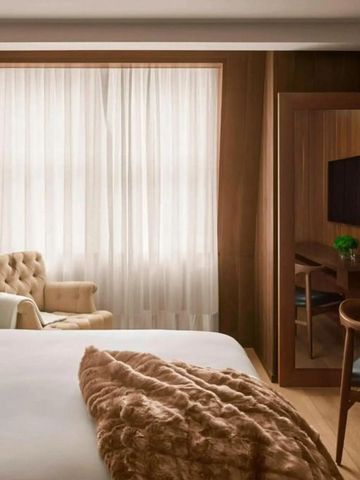 Gemütliches Hotelzimmer mit klassischem Polstersessel und Schreibtisch