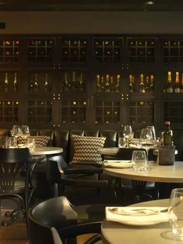 Elegantes Restaurant mit gedeckten Tischen und einer Weinwand im Hintergrund