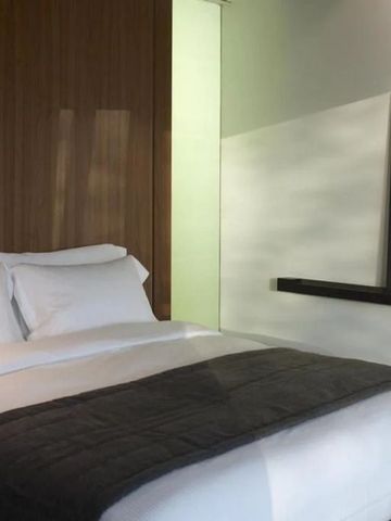 Modernes Hotelzimmer mit großem Bett, dezenter Beleuchtung und geschmackvollen Bildern an der Wand