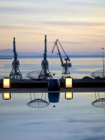 Infinity-Pool mit Blick auf Hafenkräne bei Sonnenuntergang