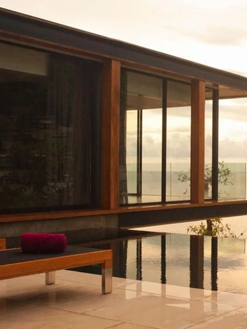 Infinity-Pool mit Blick auf den Ozean bei Sonnenuntergang vor einer Villa