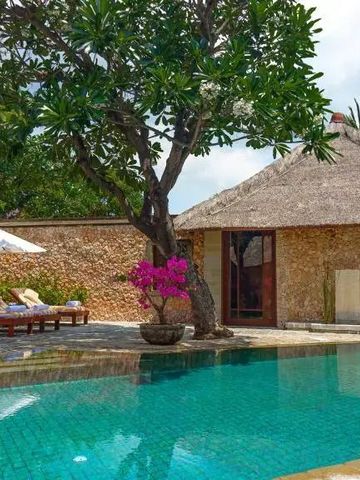 Infinity Pool mit Sonnenschirmen und Blumen neben tropischer Villa