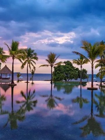 Infinity Pool mit Palmen und Meerblick im Sonnenuntergang