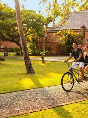 Paar auf Tandemrad in tropischem Garten bei Sonnenschein