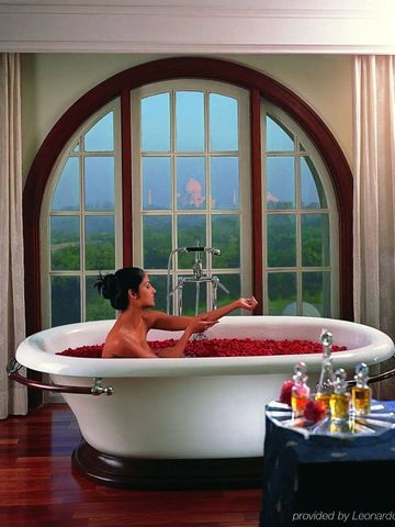 Frau in einer Badewanne mit Rosenblättern und Blick auf den Taj Mahal