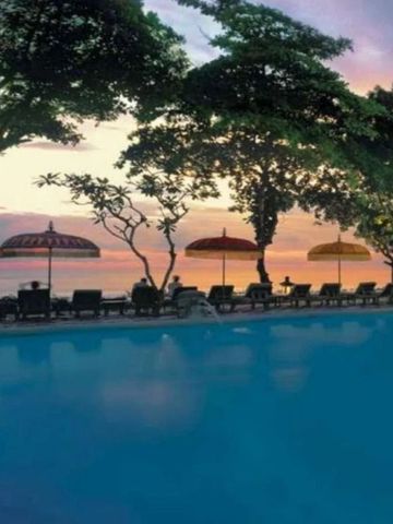 Infinity-Pool mit Sonnenuntergang am Meer und bunten Sonnenschirmen