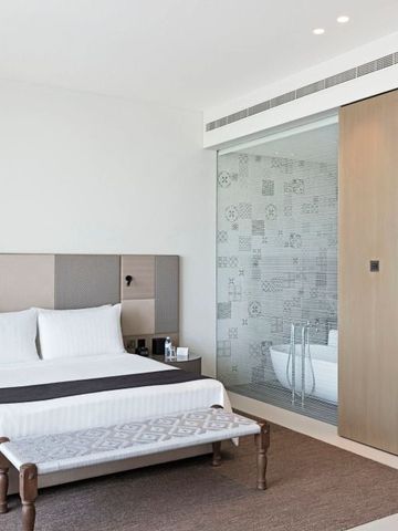 Helles Zimmer mit komfortablem Bett und luxuriösem Badezimmer im Hintergrund