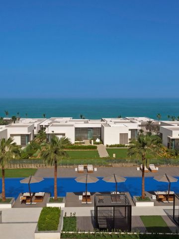 Weitblick auf luxuriöse Villen am Strand von Al Zorah mit smaragdgrünem Meer.