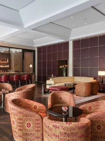 Elegante Hotelbar mit roten Sesseln und stilvoller Beleuchtung