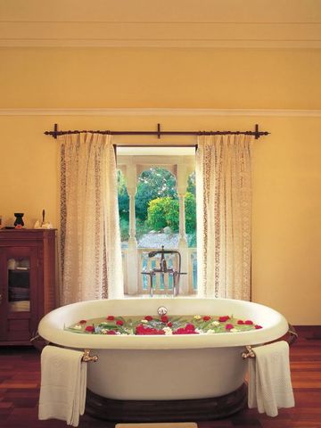 Luxuriöse freistehende Badewanne mit Rosenblättern in einem eleganten Badezimmer.