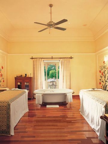 Spa-Raum mit zwei Massagetischen und einer freistehenden Badewanne.