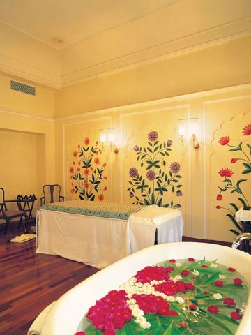 Spa-Raum mit floralen Wandmalereien und einer Badewanne mit Blüten.