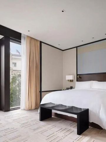 Helles Hotelzimmer mit großem Bett und bodentiefen Fenstern