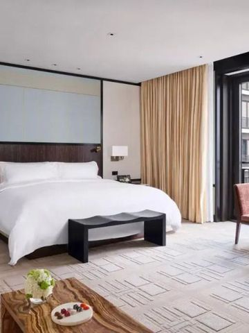 Luxuriöses Zimmer mit großem Bett und Sitzbereich vor bodentiefem Fenster