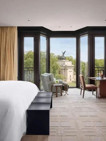 Großes Zimmer mit eleganter Einrichtung und Fenstern mit Parkblick.