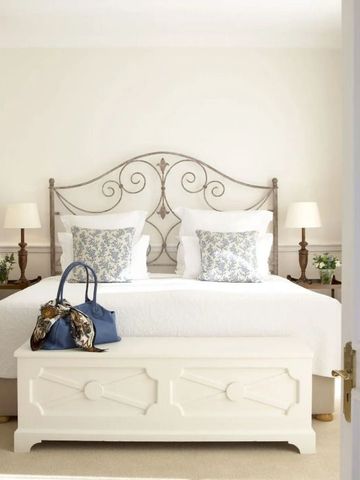 Schlafzimmer mit dekorativem Eisenkopfteil und weißen Kissen