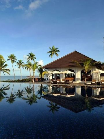 Infinity-Pool mit Blick auf das Meer und Palmen am Horizont