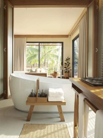 Luxuriöses Badezimmer mit freistehender Badewanne und tropischer Aussicht