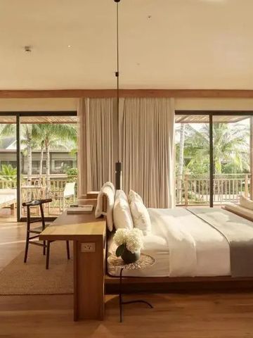 Geräumiges Hotelzimmer mit großem Bett und Blick auf tropische Vegetation