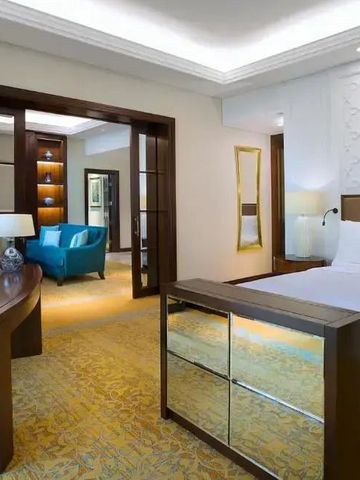 Suite mit separatem Wohnbereich. Komfortables Bett und blaue Armchairs