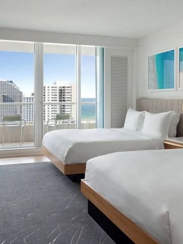 Helles Hotelzimmer mit zwei Doppelbetten und Meerblick