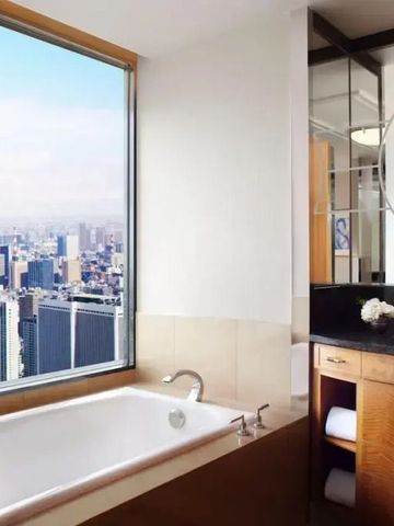 Luxuriöses Badezimmer mit atemberaubendem Blick über die Stadt von großen Fenstern.
