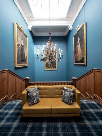 Elegante Lounge mit blauer Wand und goldener Couch in historischer Dekoration