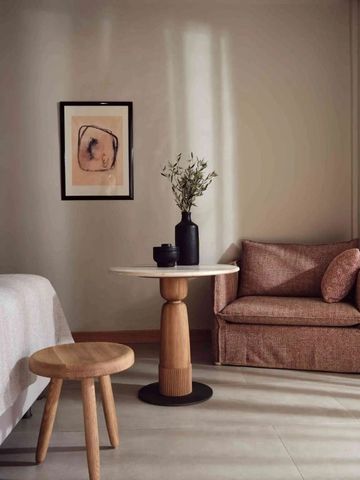 Gemütlicher Loungebereich im Hotelzimmer mit Sessel, Tisch und Kunstwerk