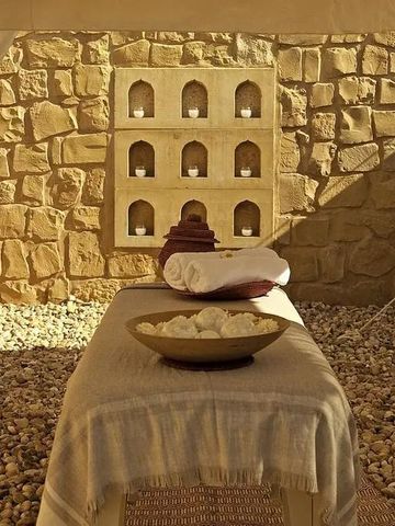 Wellnessbereich mit Massageliege und dekorativer Steinwand im SUJÁN The Serai Jaisalmer