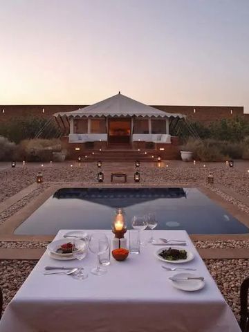 Abendessen bei Sonnenuntergang am Pool mit beleuchtetem Pavillon
