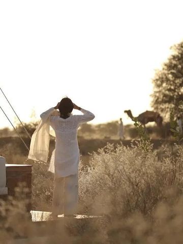 Frau im weißen Kleid genießt den Wüstenblick bei Sonnenaufgang