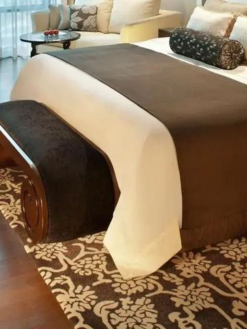 Elegantes Bett mit luxuriösem Dekor und kunstvollem Teppich.
