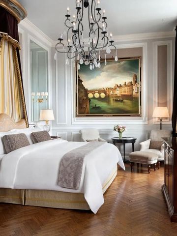 Opulentes Schlafzimmer mit Kronleuchter und klassischer Kunst an den Wänden.