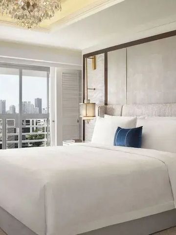 Geräumiges Hotelzimmer mit großem Bett und Stadtblick durch Fenster.