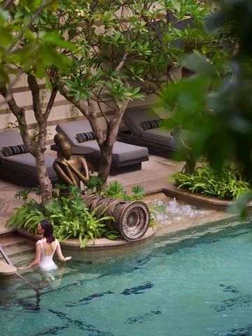 Großzügiger Pool mit grüner Umrandung und eleganten Liegen im Hintergrund