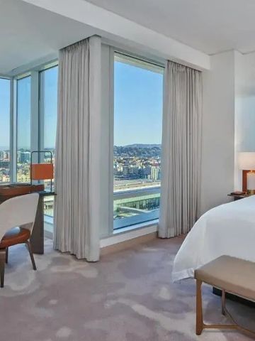 Zimmer mit großer Fensterfront, Stuhl und Tisch mit Panoramablick.
